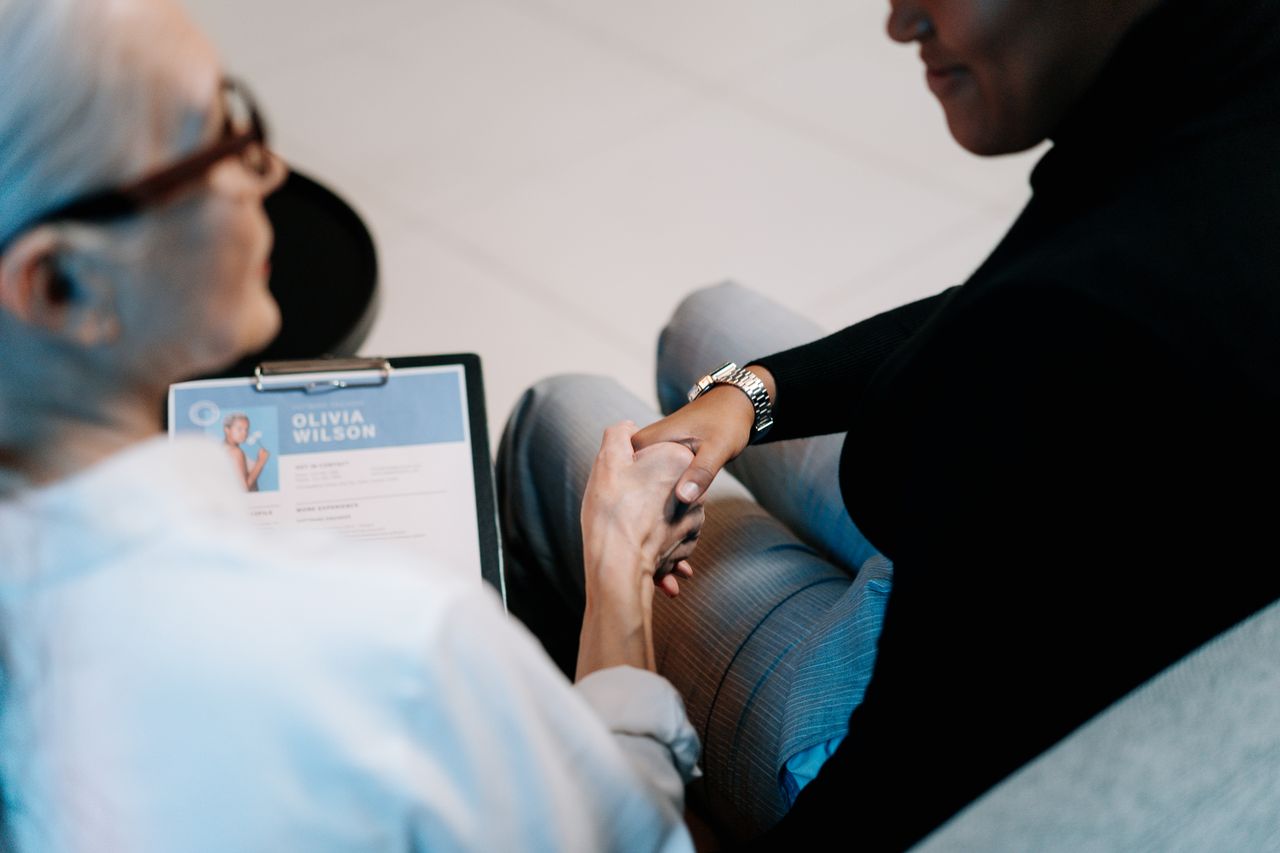 Two professional women having a handshake in an office setting, focusing on recruitment and connection.
